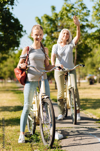 Joyful teenage girl riding a bicycle with her grandma
