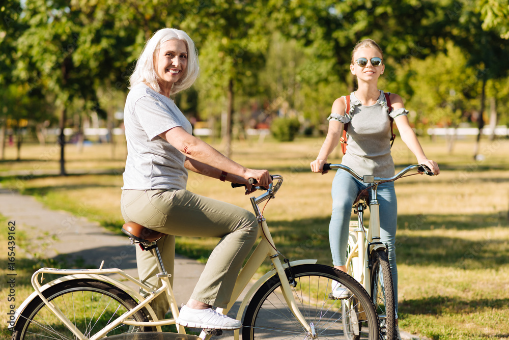 Fototapeta premium Joyful senior woman riding a bicycle with her granddaughter