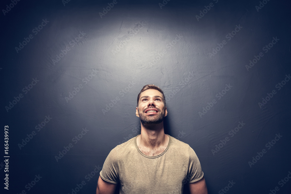 Attractive, smiling man leaning against the wall.