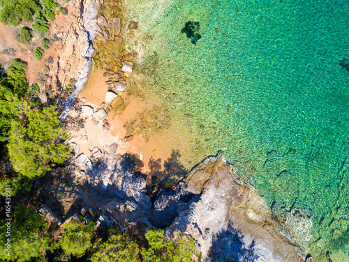 Aerial view of sandy beach with rocks and clear turquoise water