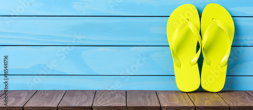 Green flip flops on wooden background. Close up
