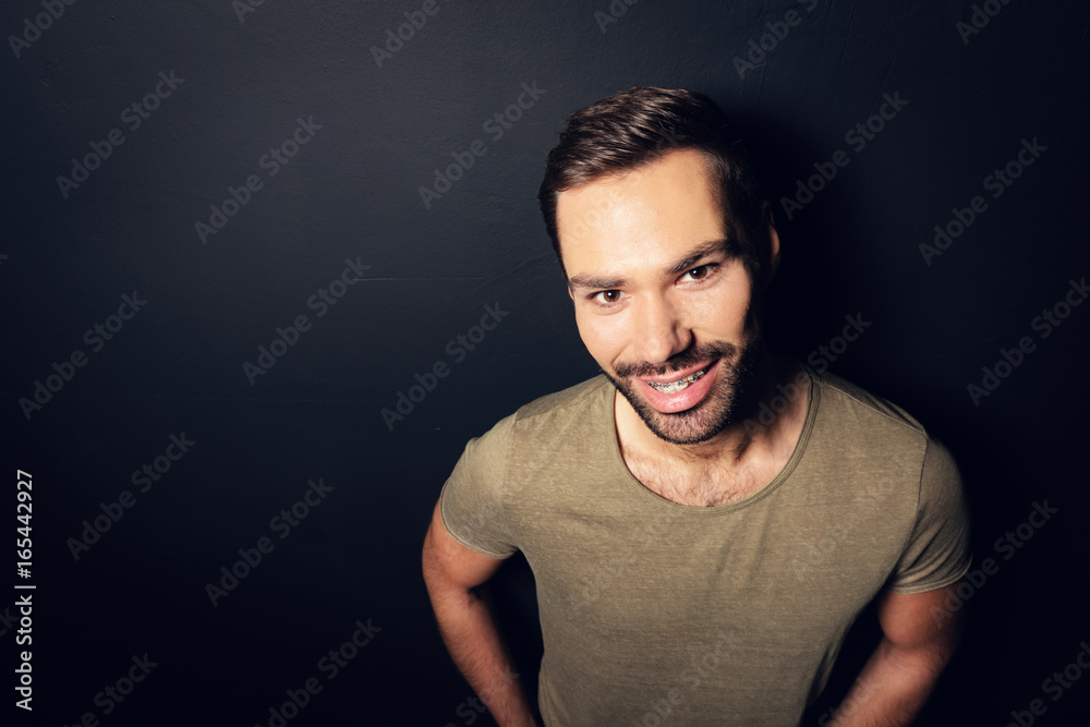Attractive, smiling man standing next to a wall.
