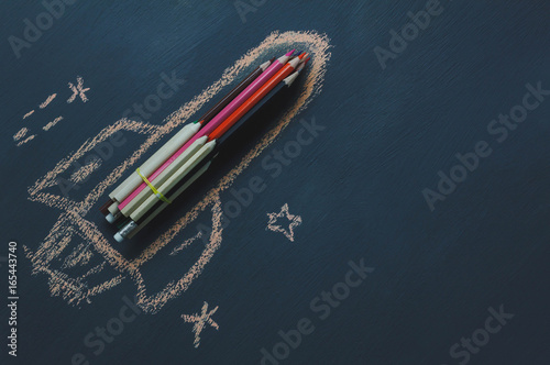 Top view rocket fling on the space with star.Crated by colorful pencil and drawing by chalk board on backboard or table.Start up business.Back to school and education concept.flat lay.copy space. © osabee