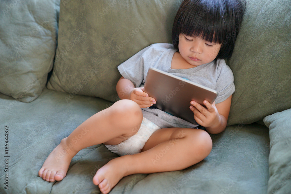 Portrait of child playing with digital tablet at home. Portrait of child playing with digital tablet at home.