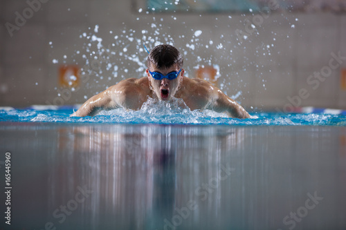 Young man swimming butterfly in indoor pool © Andrey Bandurenko