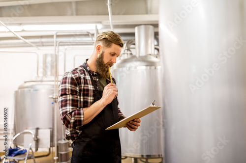 man with clipboard at craft brewery or beer plant