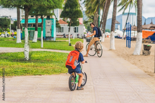 Happy family is riding bikes outdoors and smiling. Father on a bike and son on a balancebike photo