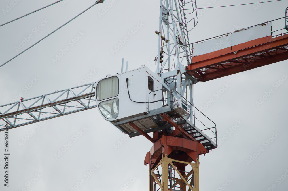 Tower crane cabin. The cockpit of a construction crane in the gray sky background