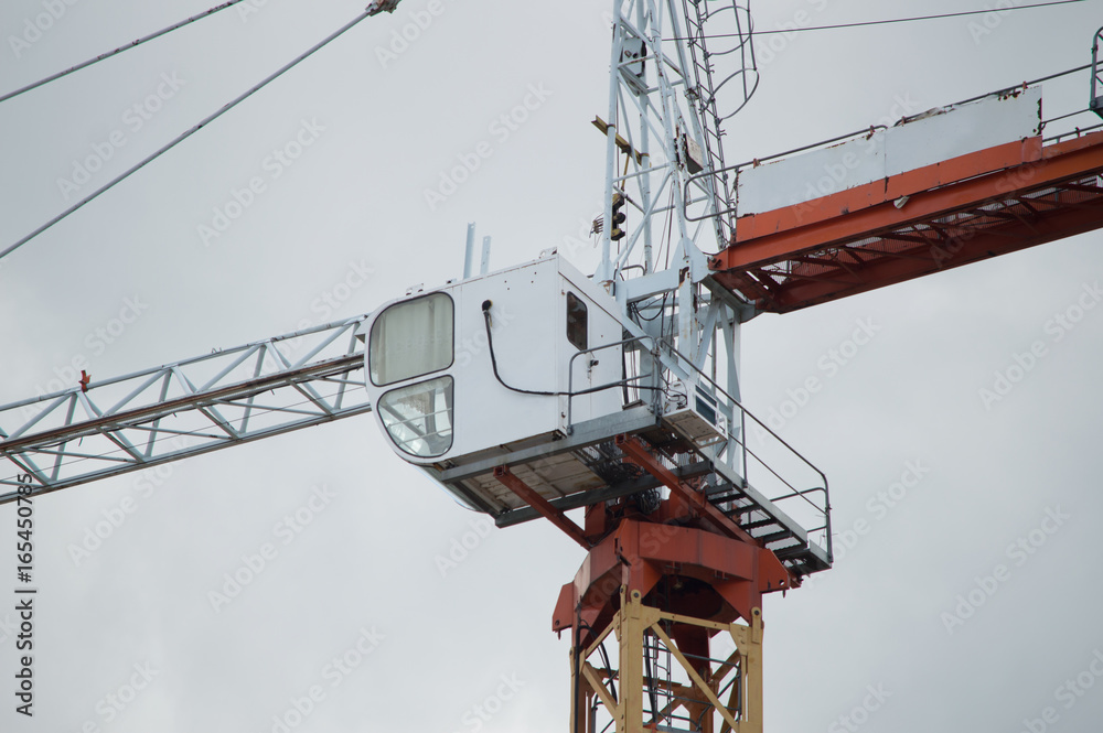 Tower crane cabin. The cockpit of a construction crane in the gray sky background Tower crane cabin. The cockpit of a construction crane in the gray sky background