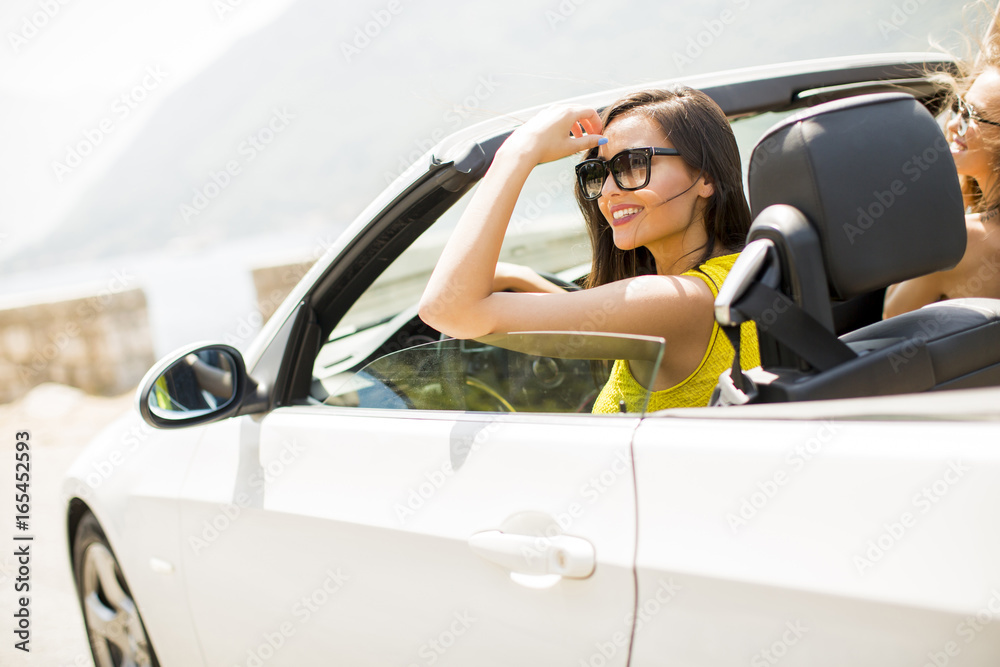 Pretty young women in white cabriolet car
