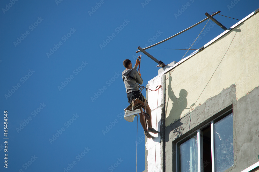 Industrial alpinism. The man in the outfit carries out work on the facade of the house Industrial alpinism. The man in the outfit carries out work on the facade of the house
