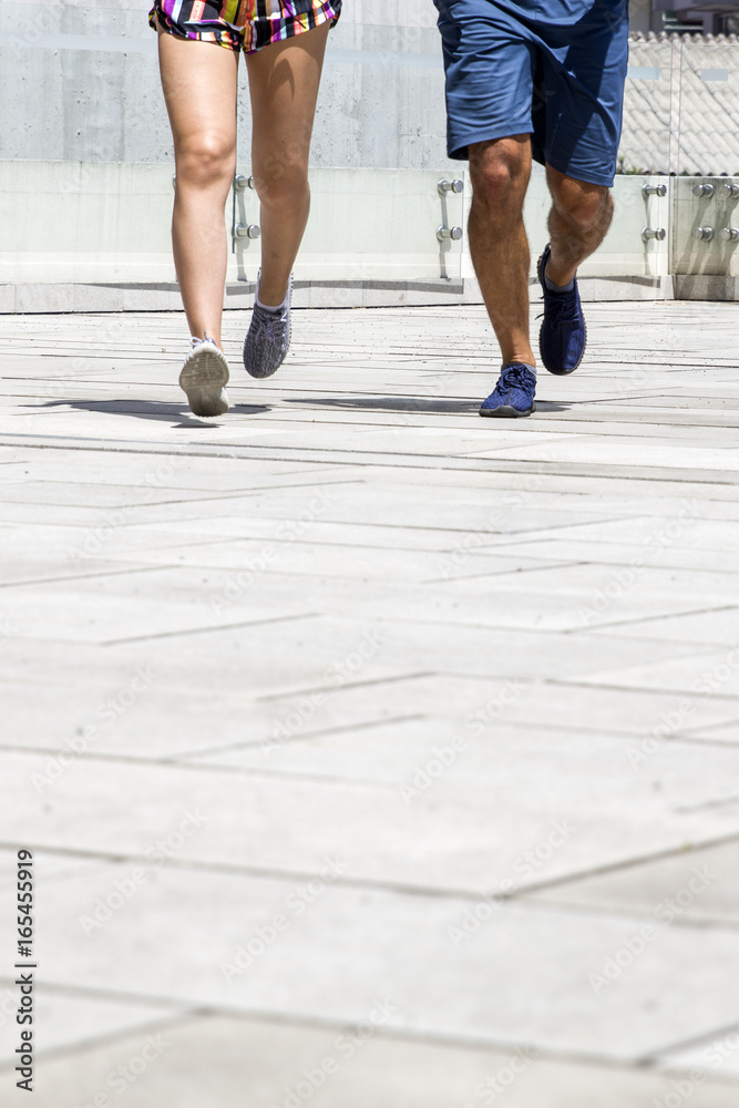 Handsome man and beautiful woman jogging together on street between residential buildings