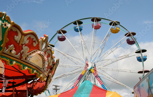Photo Fair carnival rides and tent top against blue sky.