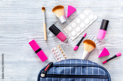 Contents of wonam's beauty bag. Cosmetics, contraceptives and pills on wooden table background top view copyspace photo