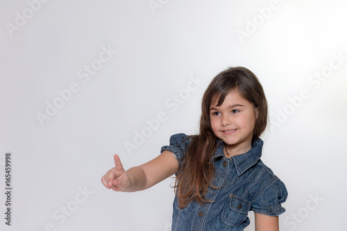 Smiling little girl is posing on the light gray background
