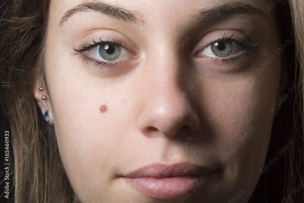 Fototapeta premium Ritratto stretto di giovane e bella ragazza che guarda con sguardo enigmatico in macchina - sfondo nero