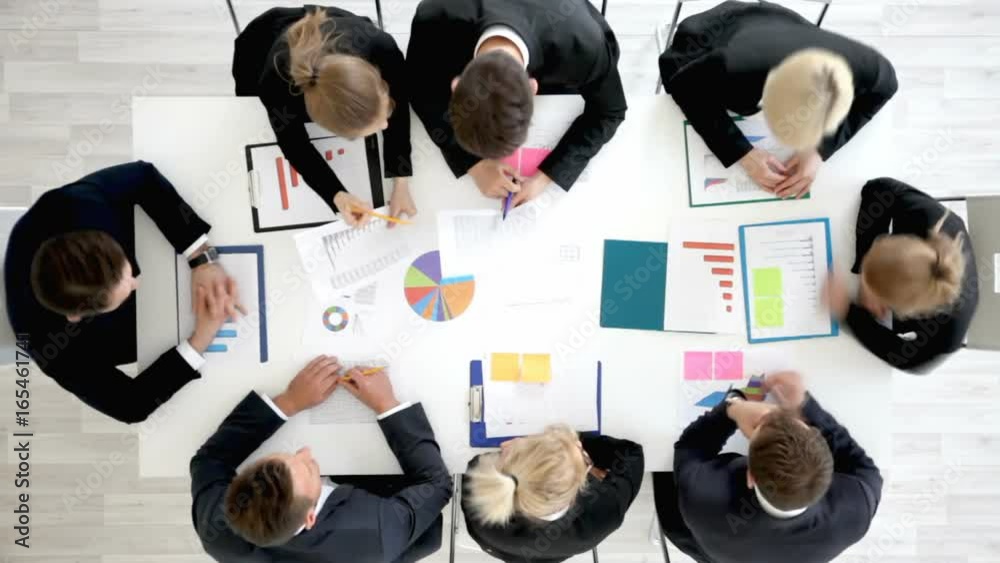 Business people work with statistics documents with tables and diagrams sitting around the table