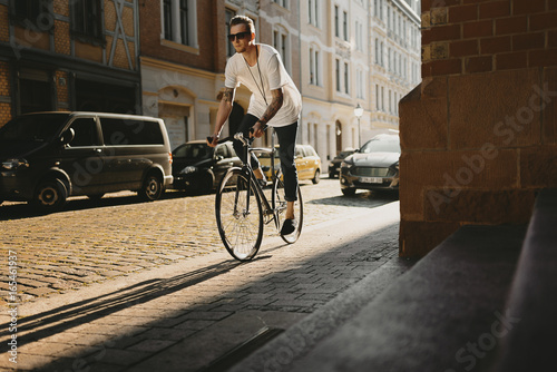 Radfahrer fährt mit Singlespeed bei Sonnenuntergang durch die Stadt