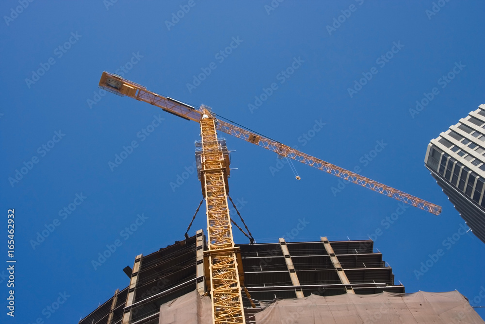 Tower crane and building construction against blue sky. Tower crane and building construction against blue sky.
