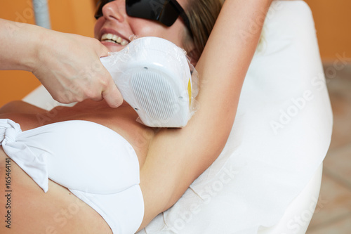 Beautician Giving Laser Epilation Treatment To Young Woman's body At Beauty Clinic