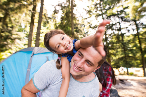 Young father with cute little daughter camping in forest.