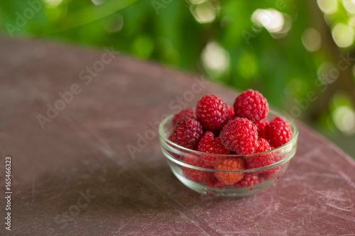 fresh raspberries in a glass bowl on a table in a gazebo