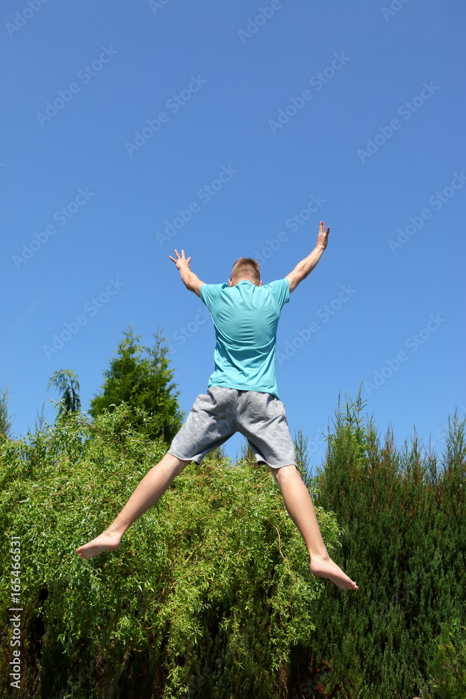 Teenager is practicing on a trampoline. Teenager is practicing on a trampoline.