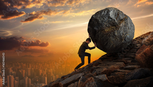 Business man pushing large stone up to hill , Business heavy tasks and problems concept. photo