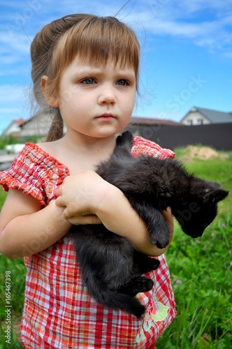 outdoor portrait of a cute little girl with small kitten, girl playing with cat on natural background