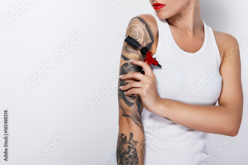 Slika na platnu Young woman tattooist with a tattoo-machine in her hand