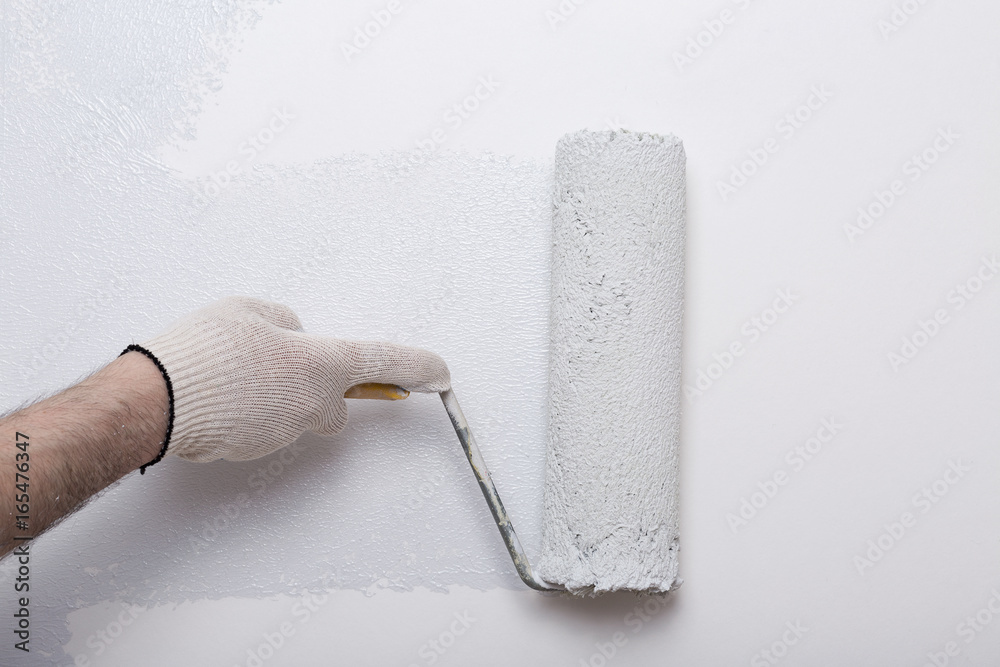 Obraz premium Close up of painter arm painting a wall in gray with paint roller