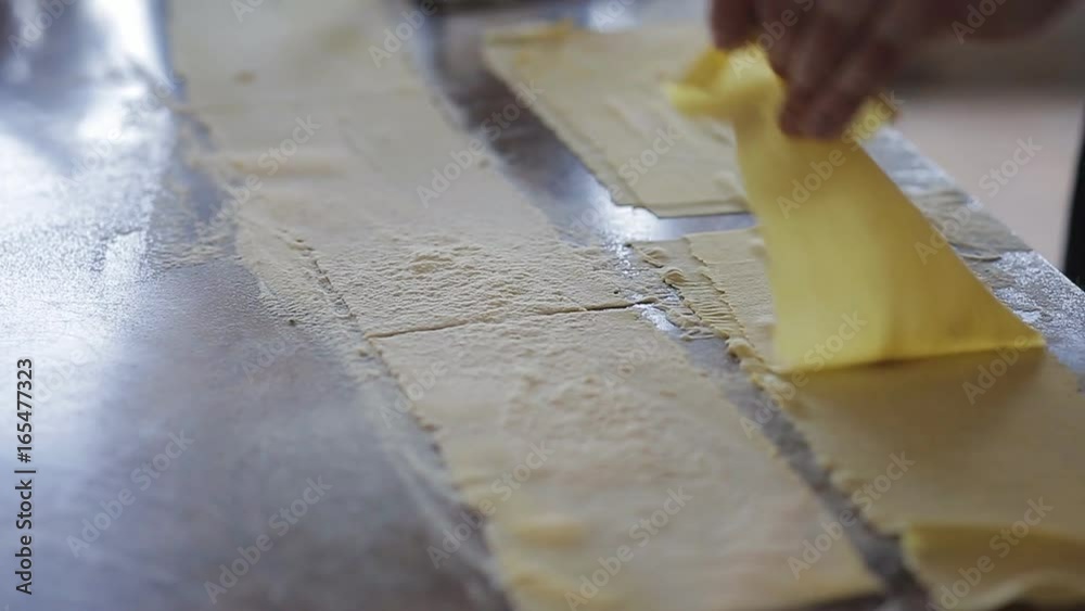 Chef's hands use a pasta cutting machine. Fresh spaghetti pasta coming out of pasta machine close-up, slow mo Chef's hands use a pasta cutting machine. Fresh spaghetti pasta coming out of pasta machine close-up, slow mo