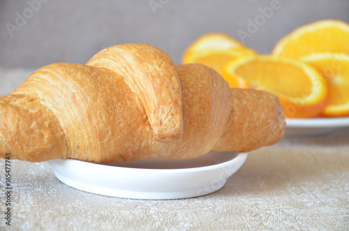 Delicious continental breakfast fresh flaky croissants with slices of orange photo