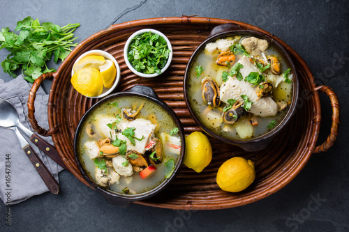 Seafood fish soup in clay bowls served with lemon and coriander. Top view, copy space