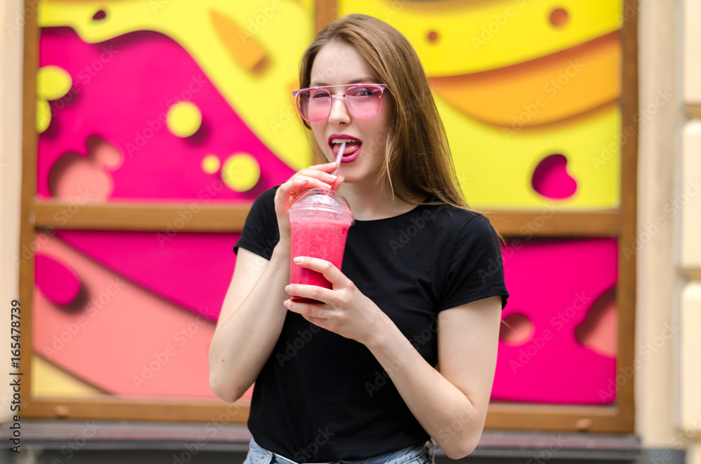 Outdoor portrait of young attractive woman with long blonde straight hair, pink glasses, pink lipstick and berry's smoothie cocktail, colorful background. Healthy food detox concept Outdoor portrait of young attractive woman with long blonde straight hair, pink glasses, pink lipstick and berry's smoothie cocktail, colorful background. Healthy food detox concept