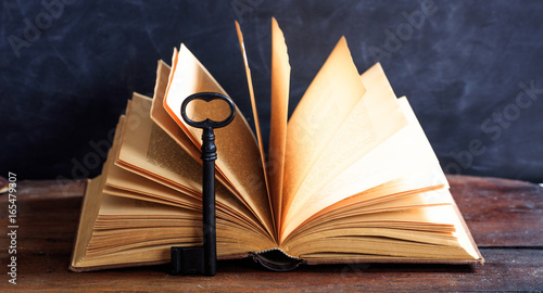 Old book and a key on a wooden desk