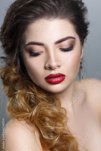 Beauty portrait of a sexy girl with a burgundy lipstick on a gray background.