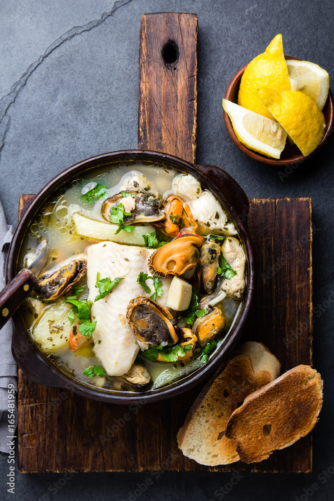 Seafood fish soup in clay bowls served with lemon and coriander. Top view, copy space Seafood fish soup in clay bowls served with lemon and coriander. Top view, copy space