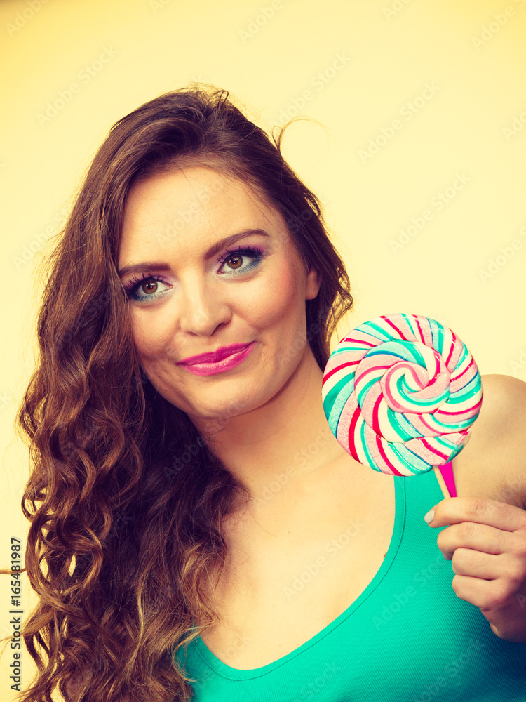 Woman charming girl with lollipop candy