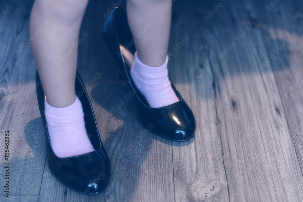 Close up of little girls feet inside adult's high heels Close up of little girls feet inside adult's high heels