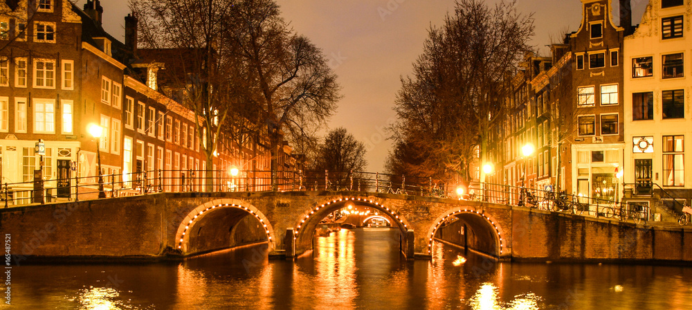 Amsterdam by night. Illuminated bridge over water canal, gracht. Netherlands