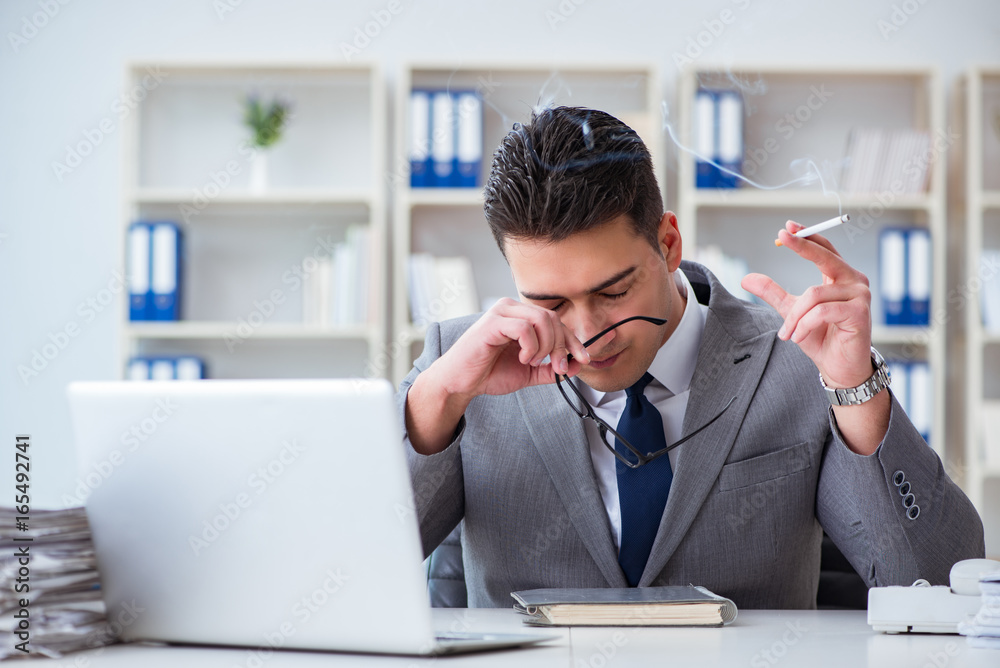 Businessman smoking in office at work Businessman smoking in office at work