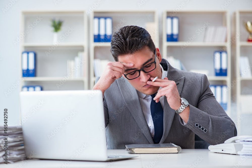 Businessman smoking in office at work Businessman smoking in office at work