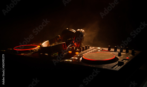DJ Spinning, Mixing, and Scratching in a Night Club, Hands of dj tweak various track controls on dj's deck, strobe lights and fog, selective focus