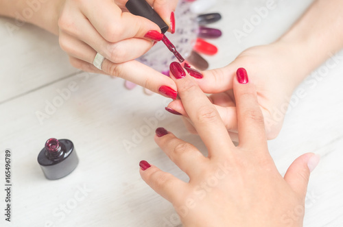 The manicurist paints the nails of women