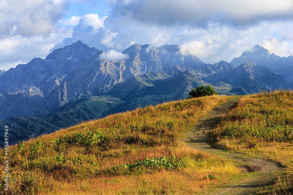 Beautiful scenic summer autumn landscape of Agepsta Peak in Caucasus Mountains in Sochi at sunset. Sunny blue sky scenery with clouds