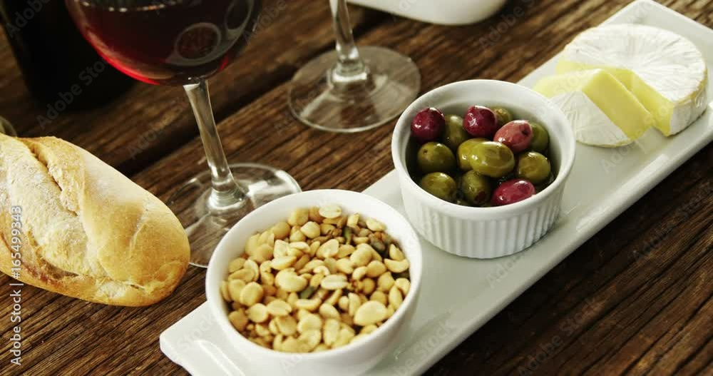 Bowl of peanuts, olives and cheese served with red wine Bowl of peanuts, olives and cheese served with red wine