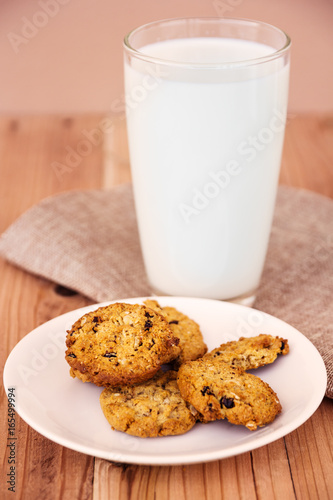 Chocolate chip cookies with milk in glass on wood table.
