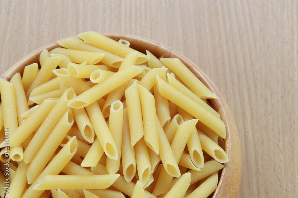 Raw Macaroni in the wooden bowl on wood background. Raw Macaroni in the wooden bowl on wood background.
