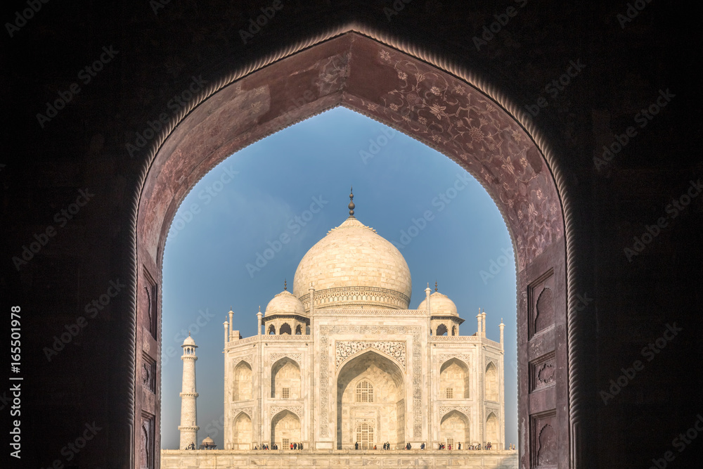 View of Taj Mahal with pool reflection in Agra India at sunrise.